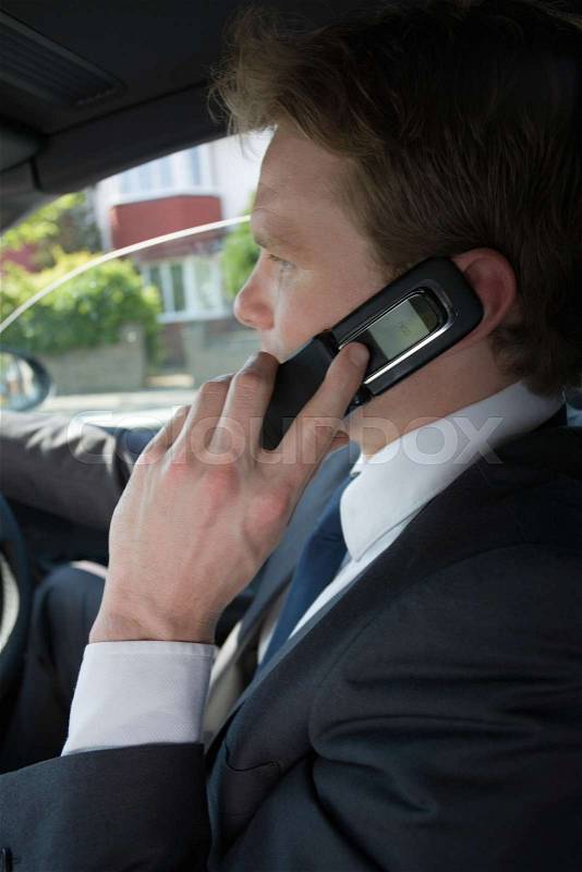 A young man using a cell phone in a car, stock photo