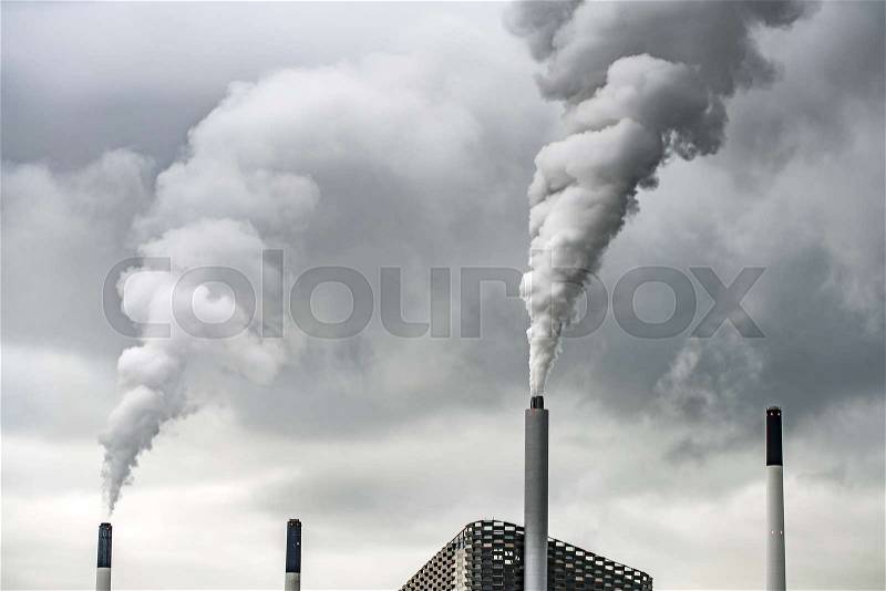 Copenhill waste-to-energy plant with steaming chimney on the background of the cloudy gray sky in Copenhagen. There are few chimneys next to it. Horizontal, stock photo