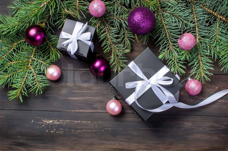 Black and white Christmas background. black gift box, pink balls, fir branches on the dark wooden background copy space, stock photo