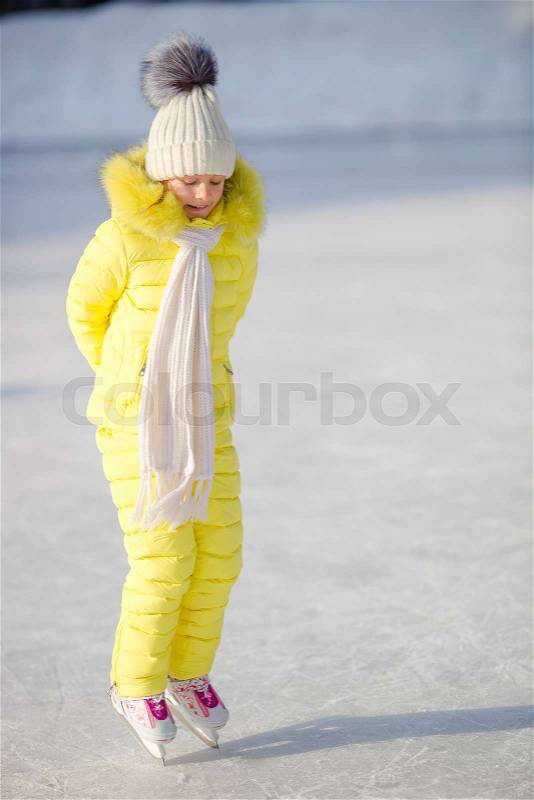 Adorable little girl skating in winter snow day outdoors, stock photo