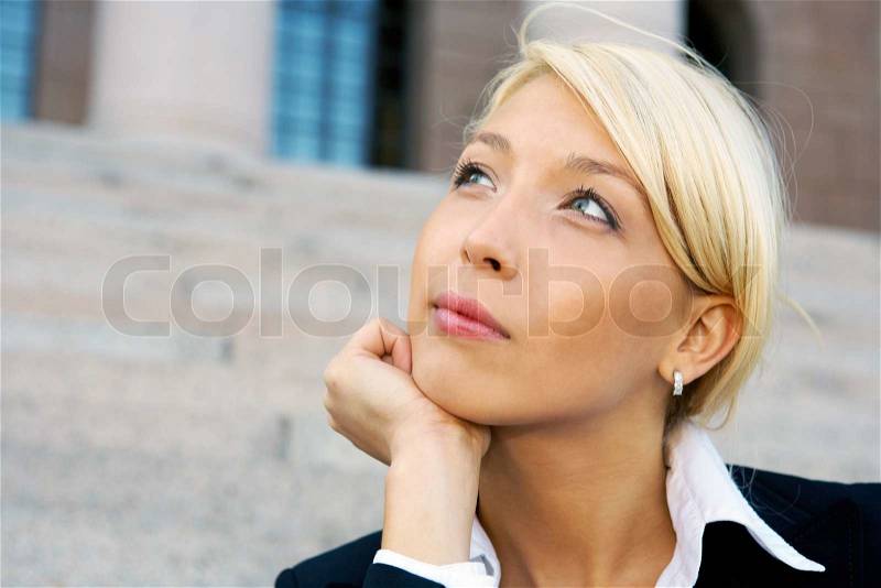 Businesswoman sitting outside building contemplating, close-up, stock photo