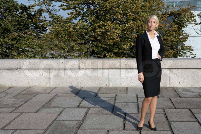 Young businesswoman standing, looking at camera, stock photo