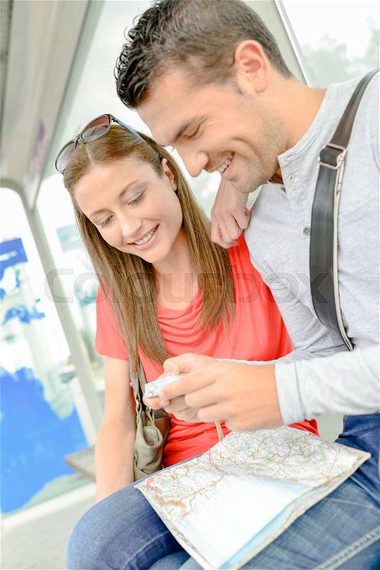 Couple on public transport, looking at photos on digital camera, stock photo