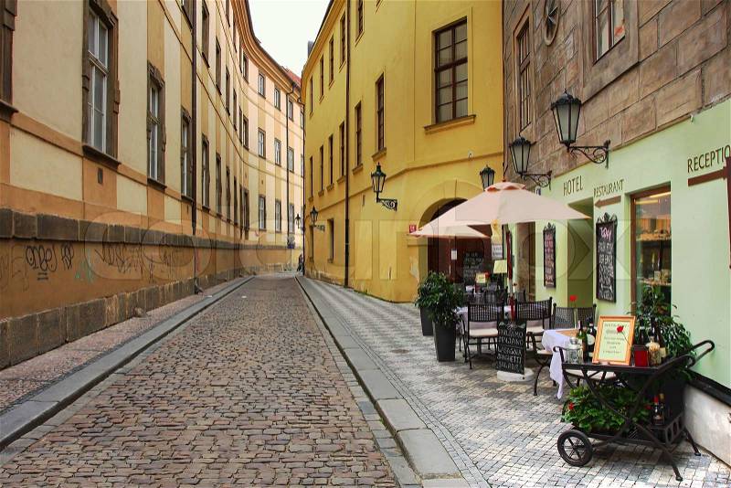 Old street with small hotel and outdoor restaurant in historic part of Prague, stock photo