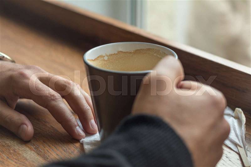 Cup of coffee in the hands of a man lying on a table in the cafe. Man drink coffee in cafe. Cozy atmosphere. Coloring and processing photo, stock photo