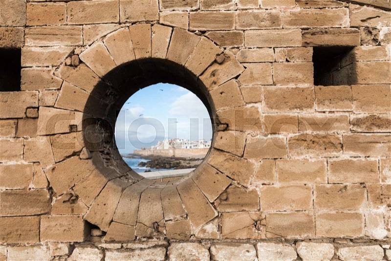 Classic view of medina Essaouira through a hole in the wall of the fortress, Morocco. UNESCO world heritage site, stock photo
