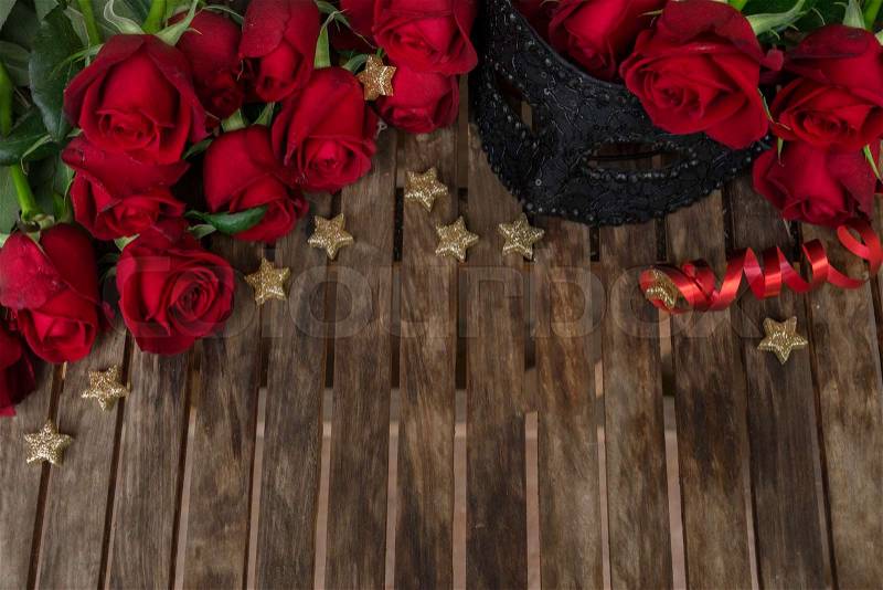 Red fresh roses with black lacy carnival masque, copy space on wooden table, stock photo