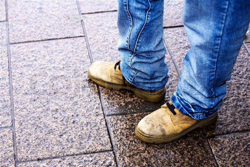 Close-up of feet of person standing in street, stock photo