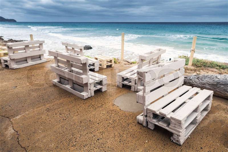Standard white wooden furniture made of cargo pallets, cheap seaside bar terrace. Porto Santo island, Madeira archipelago, Portugal, stock photo