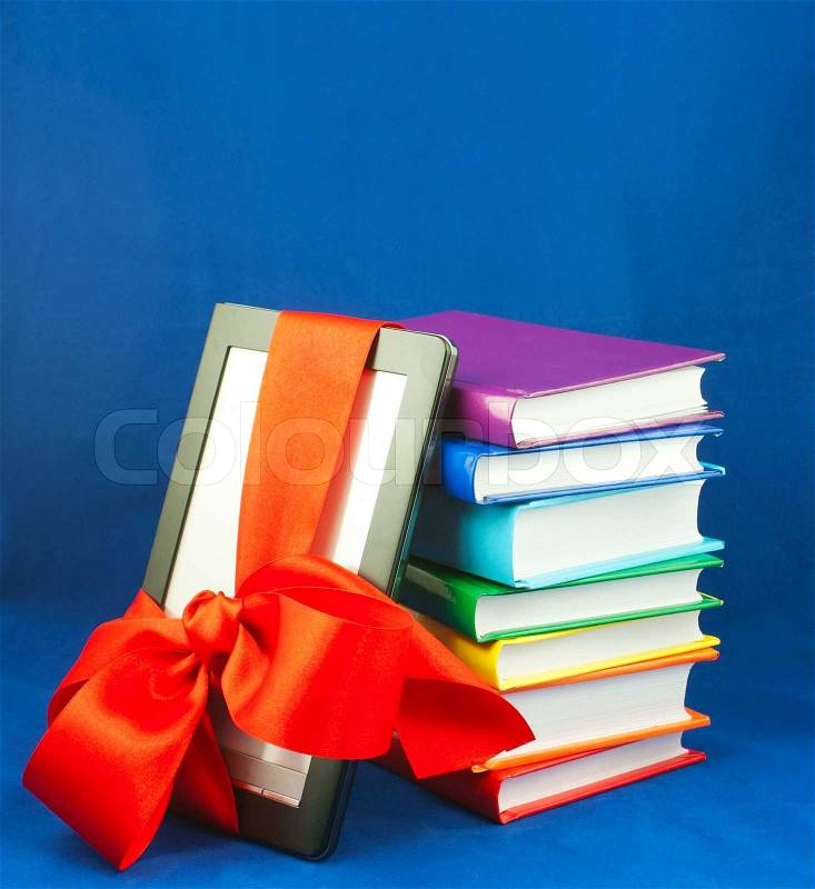 Electronic book reader tied up with red ribbon with stack of books, stock photo
