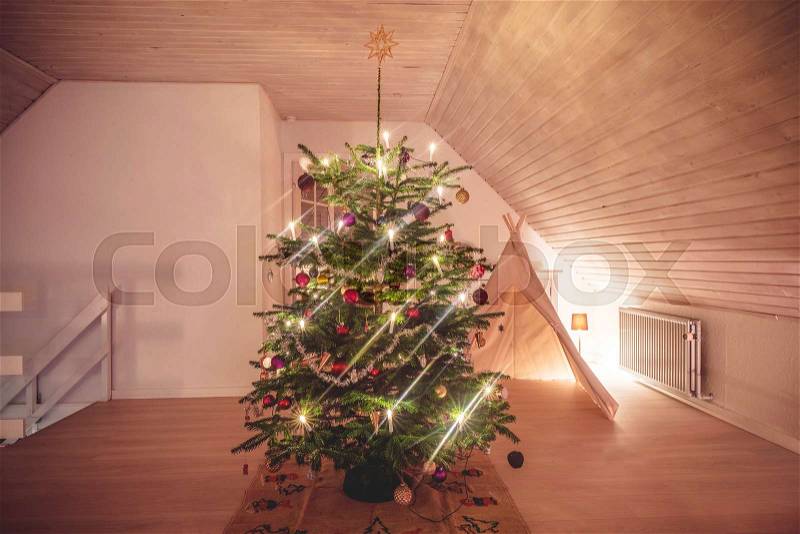 Christmas tree with glittering lights in a living room in the holidays decorated with baubles and a tent in the background, stock photo