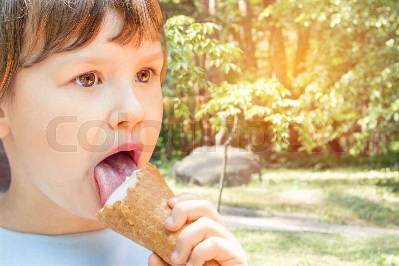 Cute little girl eating ice-cream in the city park on a summer sunny day. Portrait little girl with copy space, stock photo