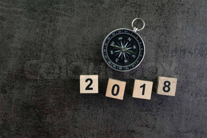 Year 2018 prediction or direction concept with compass and wooden block number 2018 on dark black background, stock photo