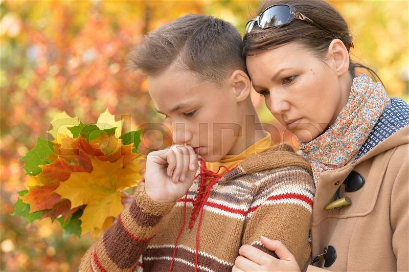 Portrait of sad mother and son in autumnal park, stock photo