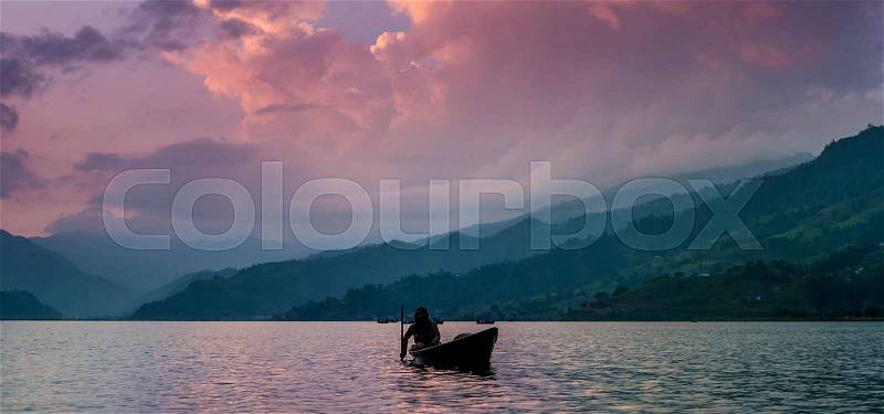 Fisherman in a boat on the lake in Pokhara at sunset, stock photo