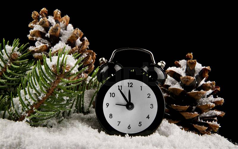 Clock, cone and snow on a black background, stock photo