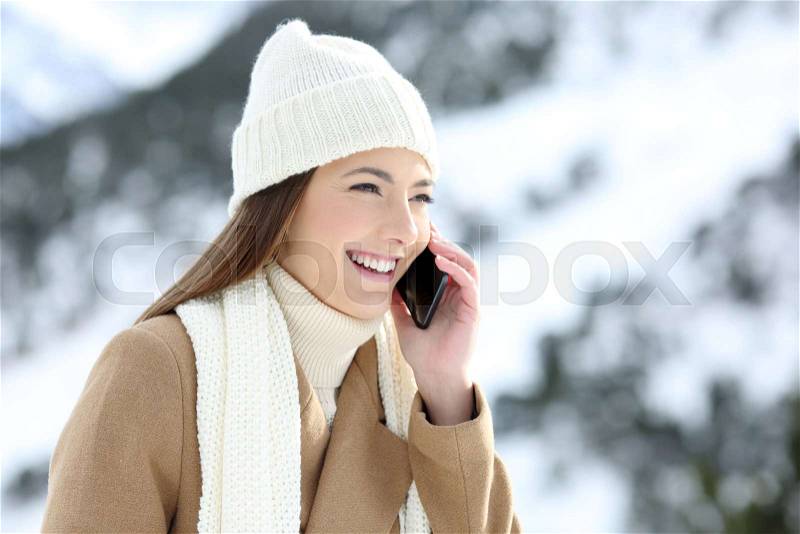 Happy woman having a phone conversation in winter holidays in a snowy mountain, stock photo