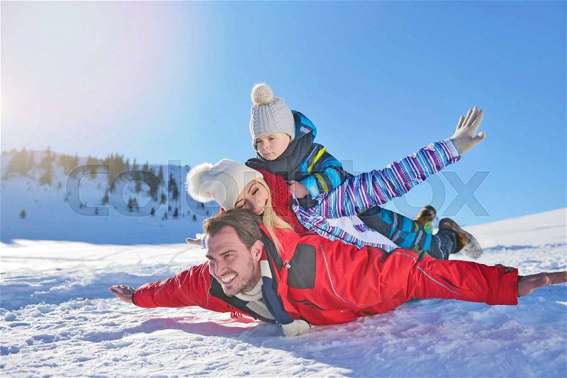 Happy young family playing in fresh snow at beautiful sunny winter day outdoor in nature, stock photo