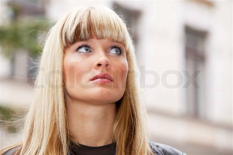 Portrait of young woman in city, looking away, stock photo