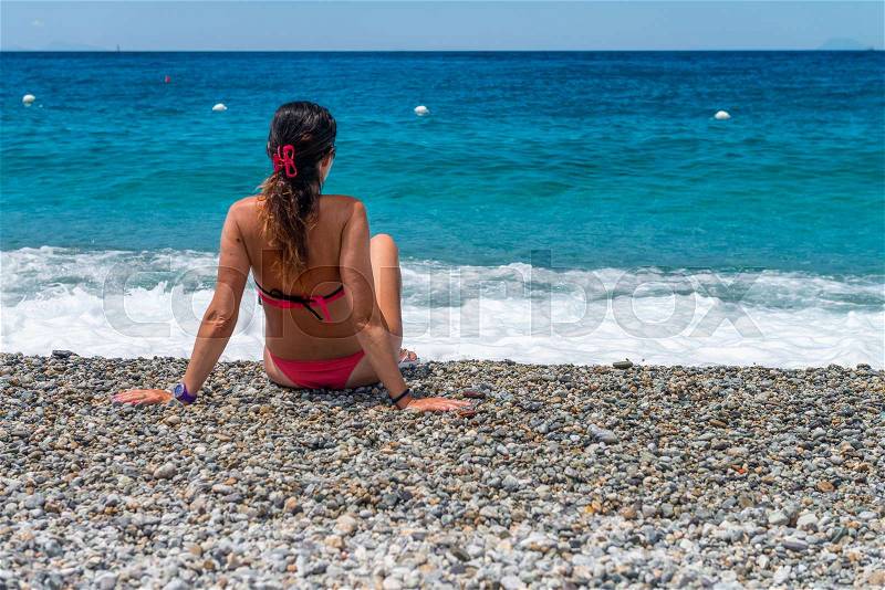 Beautiful woman looking at the ocean from the beach, back view. Travel concept, stock photo