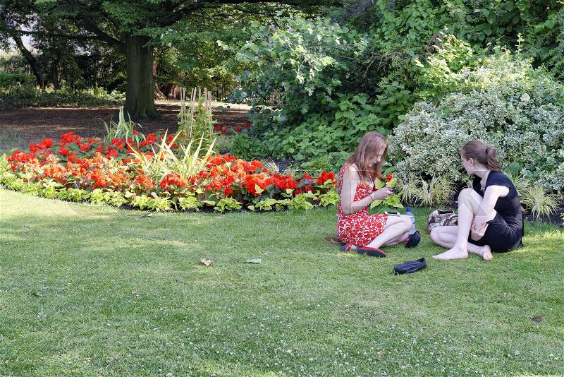 LONDON - MAY 2015: Female friends relax in a city park. London attracts 30 million tourists annually, stock photo