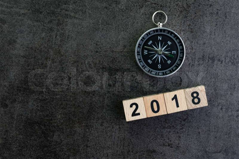 Compass and wooden block number 2018 on dark black background as year 2018 prediction or direction concept, stock photo