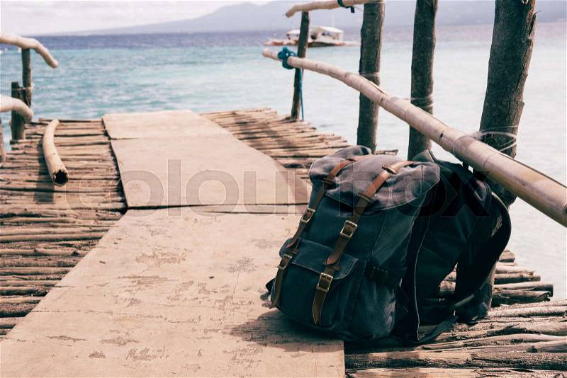 Backpack bags put down on coastline wooden bridge over blue natural seashore, stock photo