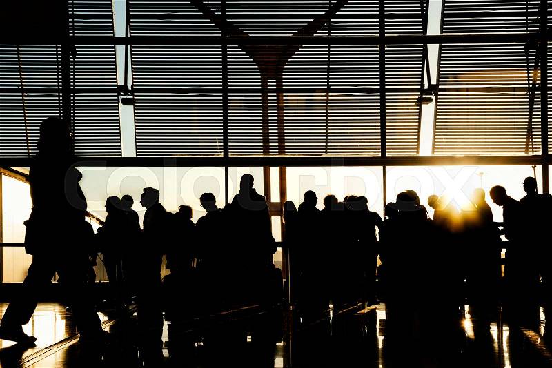 Silhouettes of business people traveling on airport; waiting at the plane boarding gates, stock photo