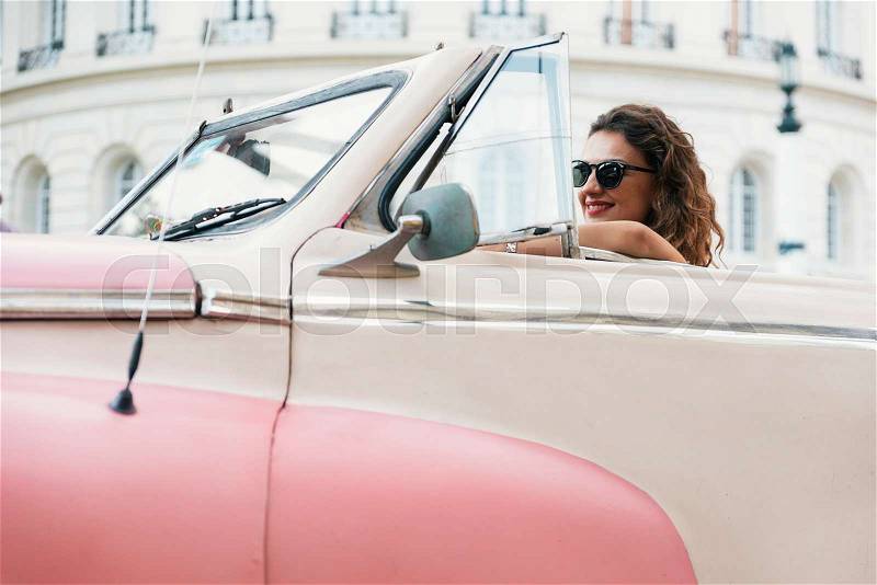 Beautiful woman tourist enjoying vacation holidays in Cuba driving a classic car, stock photo