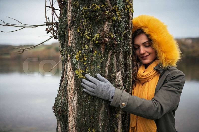 Beautiful woman in the forest hugging a tree. Nature concept, stock photo