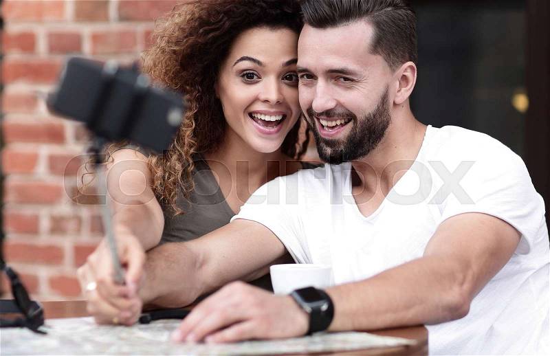 Happy cheerful couple sitting down at a cafe and making selfie, stock photo