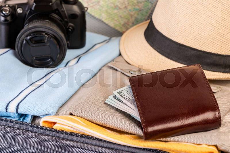 Wallet with money, camera and clothing close-up in suitcase, stock photo