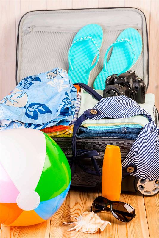 Open packed suitcase with things collected for vacation, stock photo