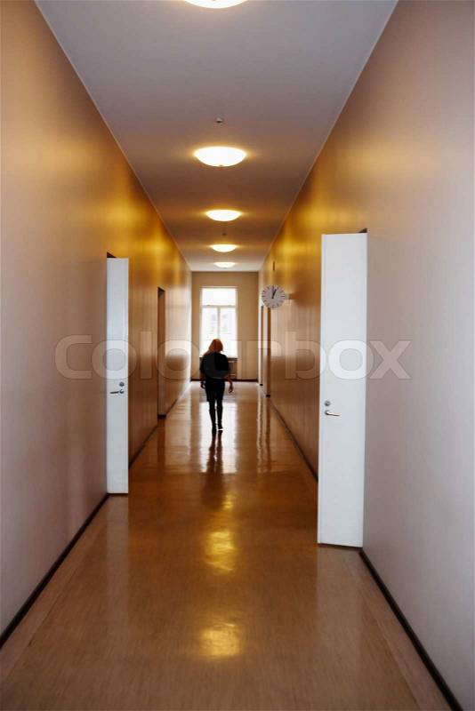 Woman in corridor, walking away, open doors, stock photo