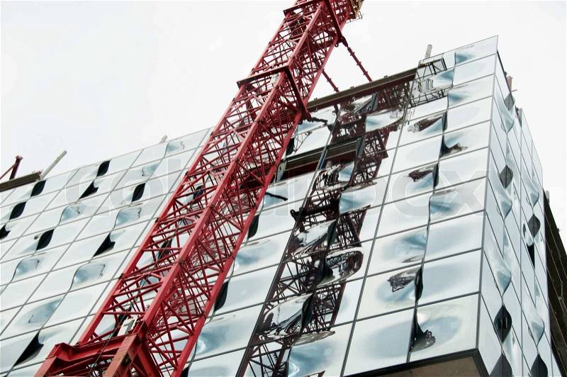 Construction site of the new Elbphilharmonie philharmonic concert hall in Hamburg showing the great window construction no two windows are the same and a crane with shadows, stock photo