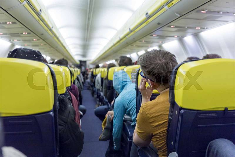 Interior of low priced commercial airplane with passengers on seats, stock photo