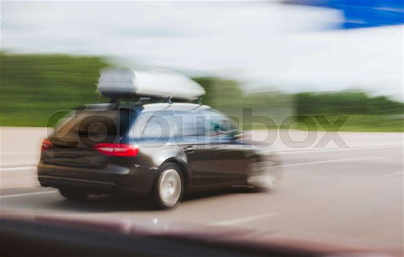 Cargo carrier on top of wagon car driving fast on highway autobahn to destination of the upcoming holiday, stock photo