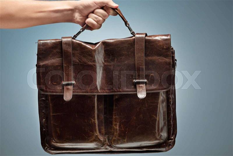 A man holding a brown leather retro bag in her hand, stock photo
