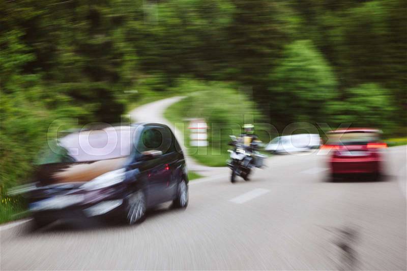Accident situation with motorcycle and two cars on highway surrounded by tree forest, stock photo