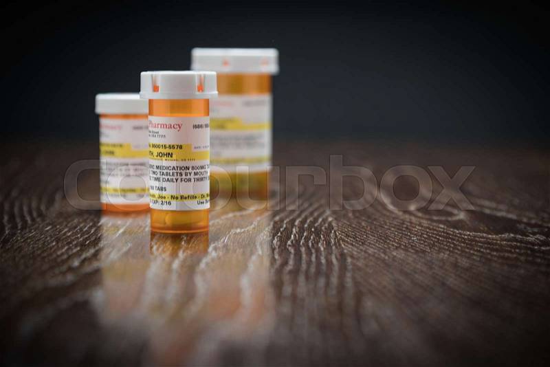 Variety of Non-Proprietary Prescription Medicine Bottles on Reflective Wooden Surface, stock photo