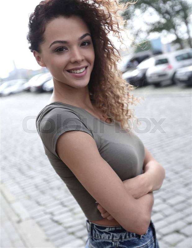 Young woman with afro hairstyle smiling in urban background, stock photo