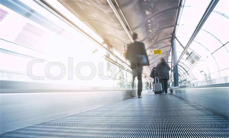 A Blurred passangers in motion on a skywalk in a modern airport. ideal for websites and magazines layouts, stock photo