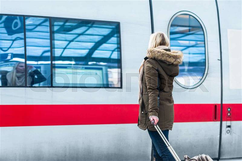 Woman waiting for her train with luggage in station ready to travel , stock photo