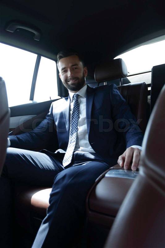 Confident businessman sitting in the back seat of a car, stock photo