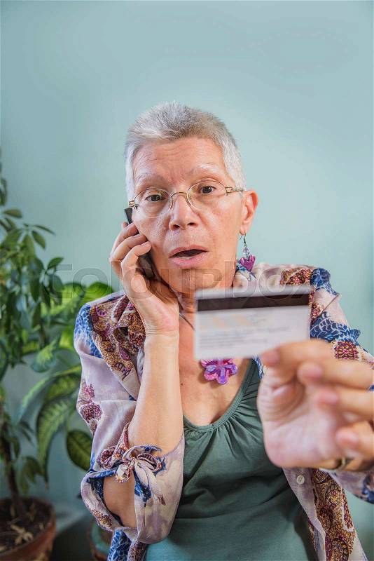 Senior lady arguing with a bank clerk over her credit card balance, stock photo