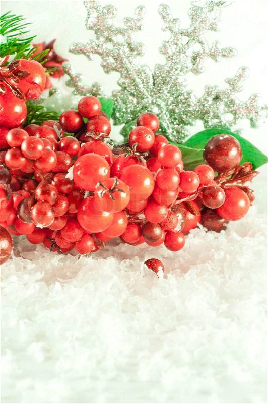Christmas branch of berries with a silver decorative snowflake against snow, stock photo