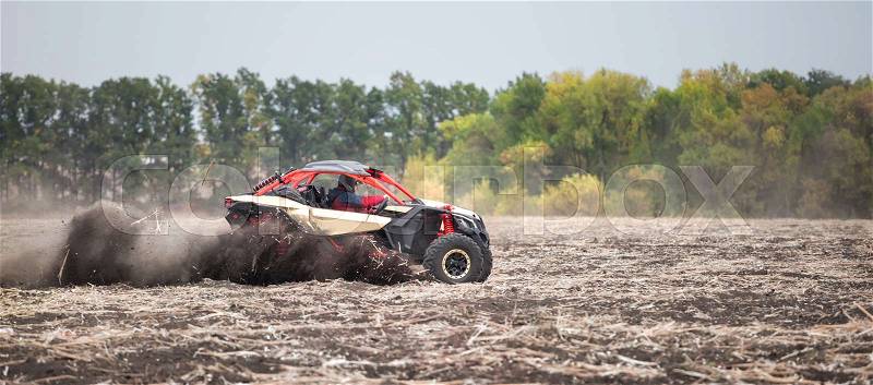 Quad bike with an men at the wheel rushes through the field in the dust. The concept of power and freedom, stock photo