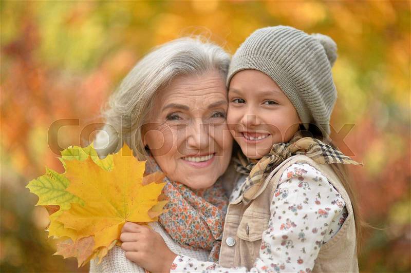 Portrait of smiling grandmother and granddaughter outdoors, stock photo