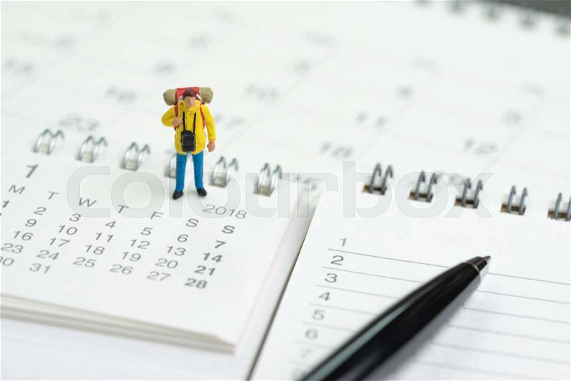 Travel, vacation or holiday calendar year plan concept, miniature traveller backpacker man figure standing on pile of calendars and numbers listed of wish list to go and pen to write destinations, stock photo