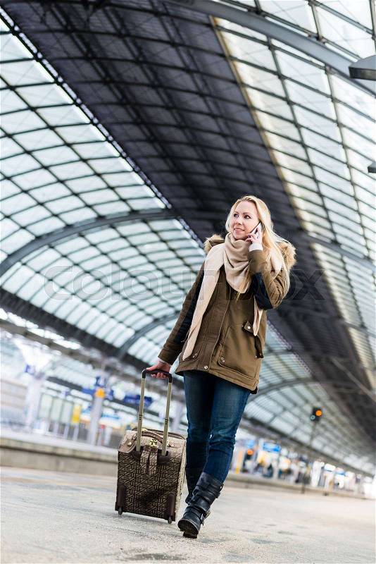 Woman with her luggage walking along the platform in train station after arriving , stock photo